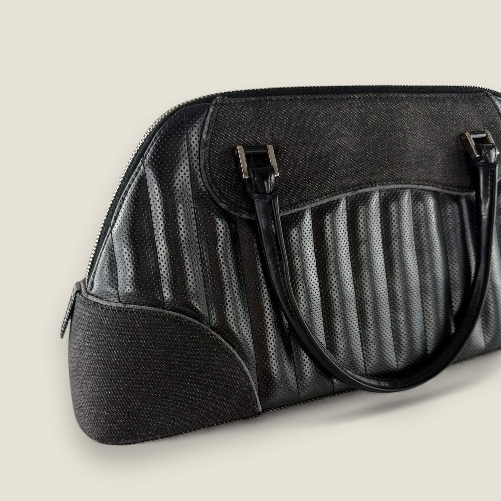 Vintage Dior bag with black perforated leather and denim accents, bold and elegant contrast